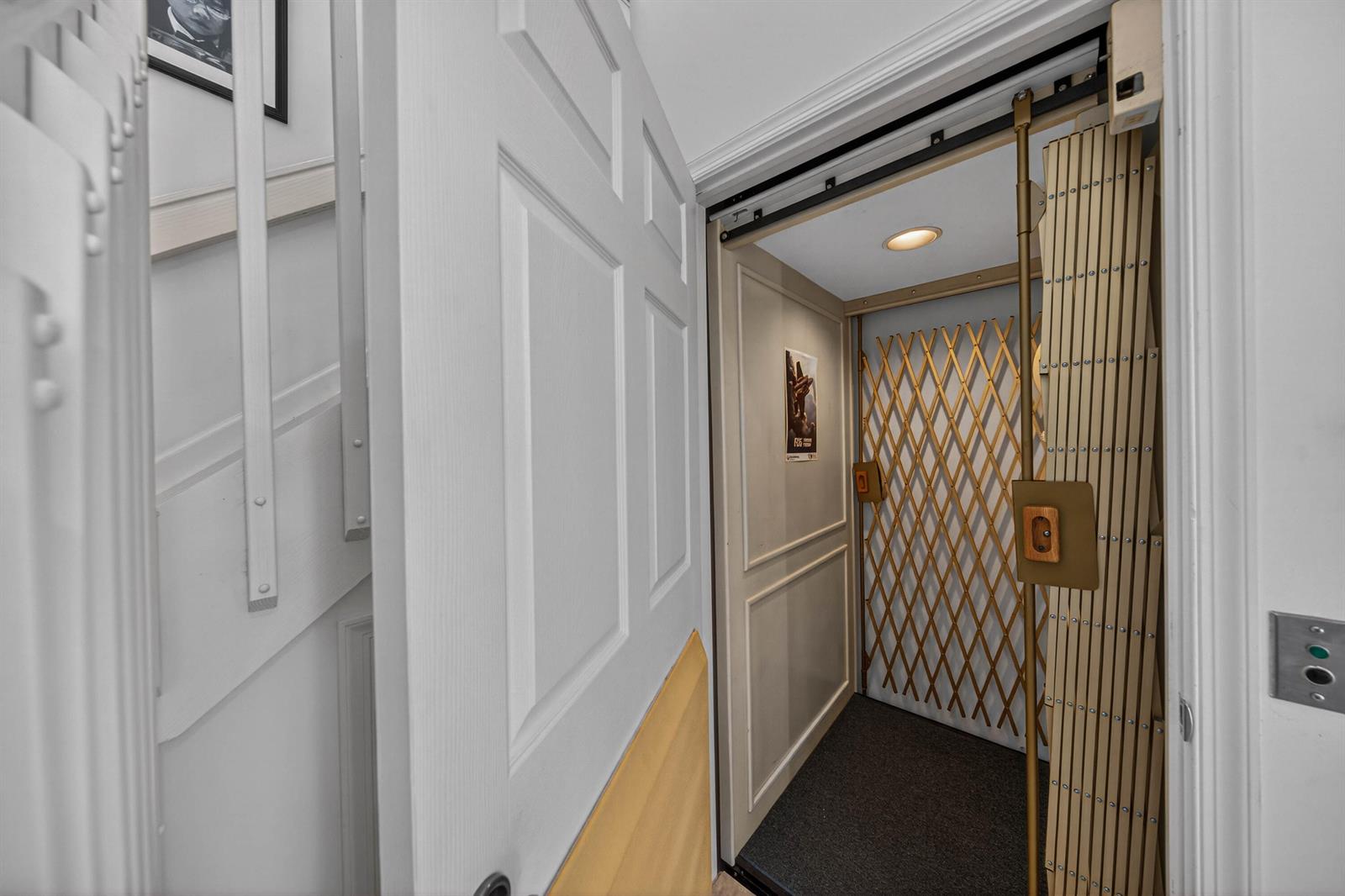 A residential elevator with a folding metal gate sits beside a white staircase — 7676 Springwater Place # 201, Boynton Beach FL 33437, BOYNTON BEACH, FL