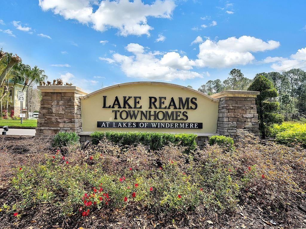 A stone-based monument sign displays the name Lake Reams Townhomes at Lakes of Windermere — 12740 LANGSTAFF DRIVE, WINDERMERE, FL