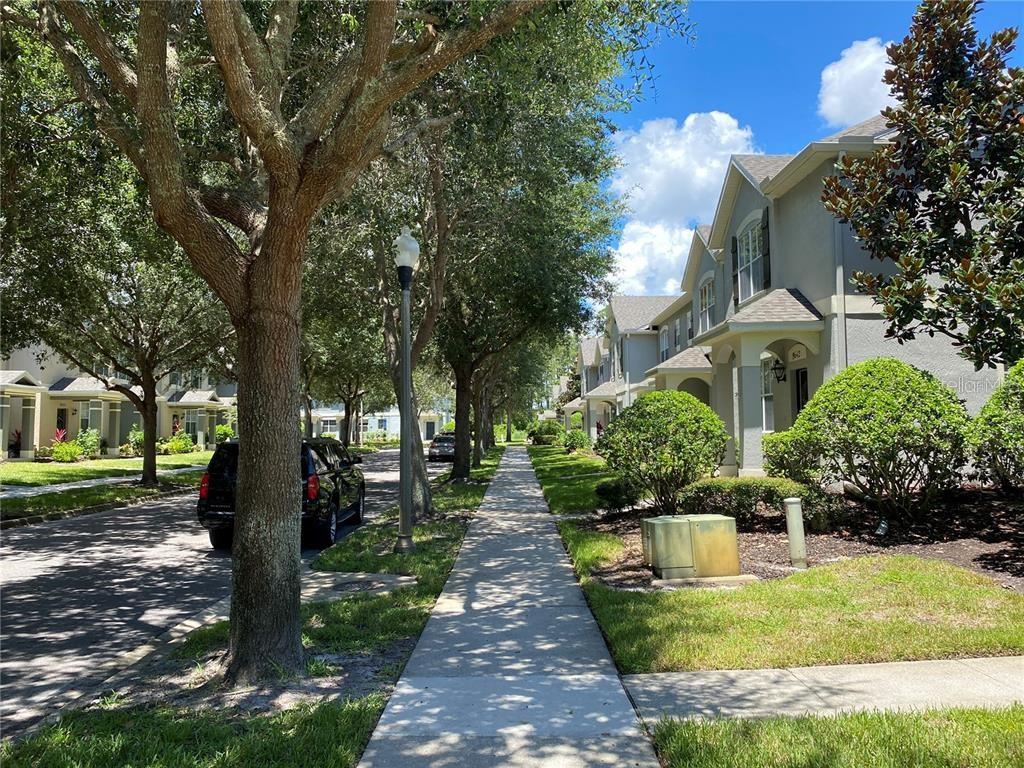 A sidewalk runs between a tree-lined street with parked cars and a row of townhouses — 12740 LANGSTAFF DRIVE, WINDERMERE, FL