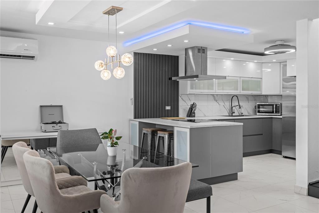A modern kitchen and dining area features gray cabinetry, a glass table, and blue lighting — 1500 LOR ROMEROS AVENUE UNIT 1220, SAN JUAN, PR
