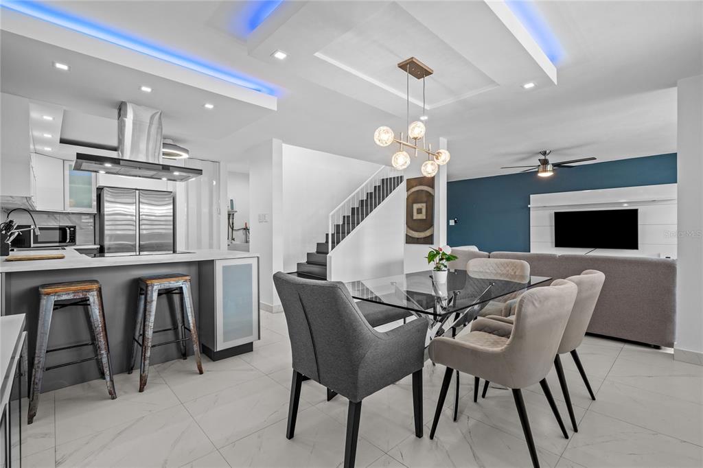 An open-concept kitchen and dining area features modern lighting, a glass table, and tile floors — 1500 LOR ROMEROS AVENUE UNIT 1220, SAN JUAN, PR