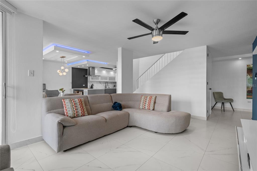 A modern living room features a light gray sectional sofa, white tile floors, and stairs — 1500 LOR ROMEROS AVENUE UNIT 1220, SAN JUAN, PR