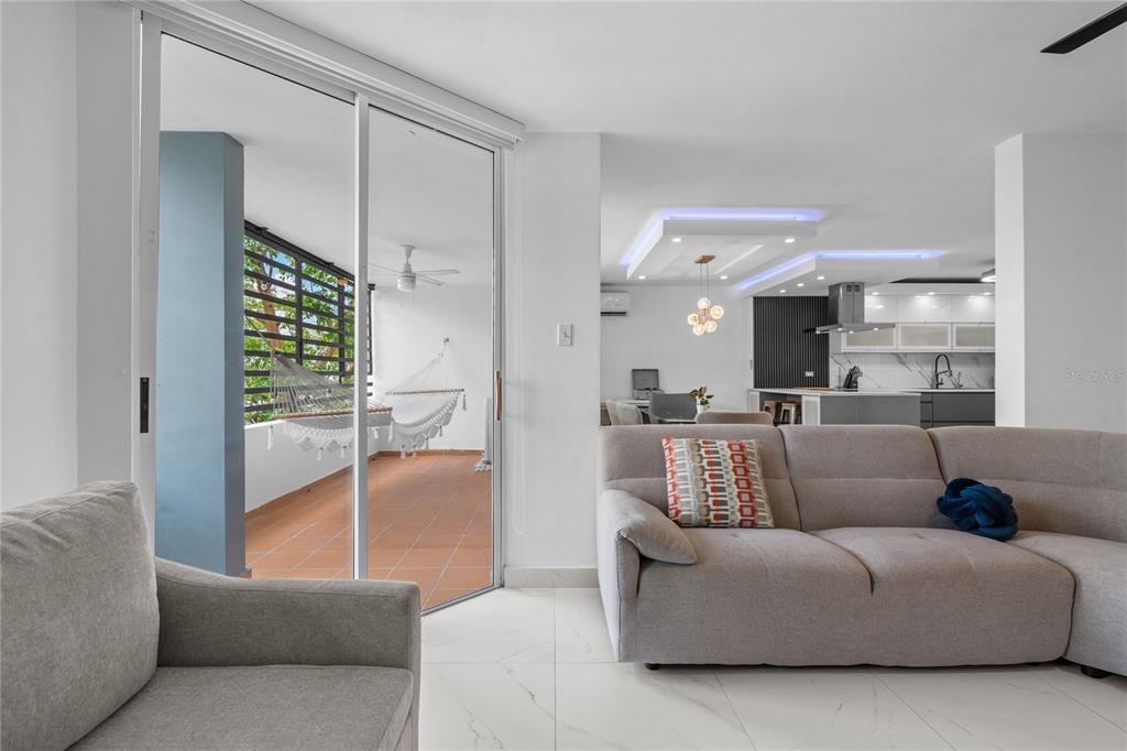 A living room with a gray sectional sofa opens to a balcony with a hammock — 1500 LOR ROMEROS AVENUE UNIT 1220, SAN JUAN, PR