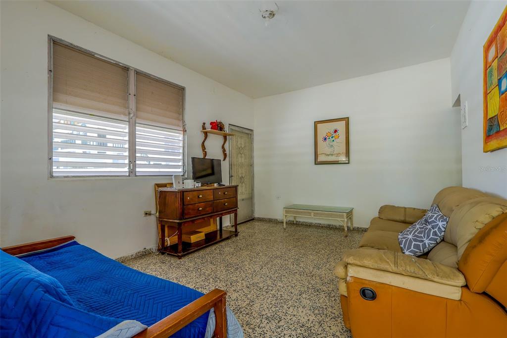 A living room features a blue futon, a tan sofa, a wooden dresser, and terrazzo flooring — 2244 REPARTO MATIAS, RINCON, PR