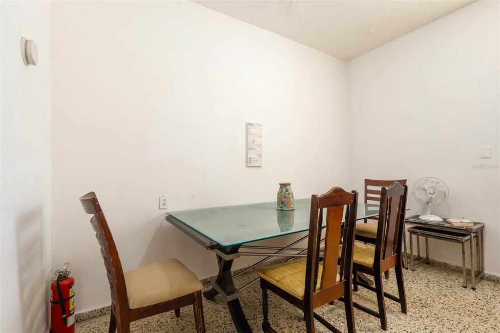 A dining room features a glass-topped table, four wooden chairs, and a fire extinguisher — 2244 REPARTO MATIAS, RINCON, PR
