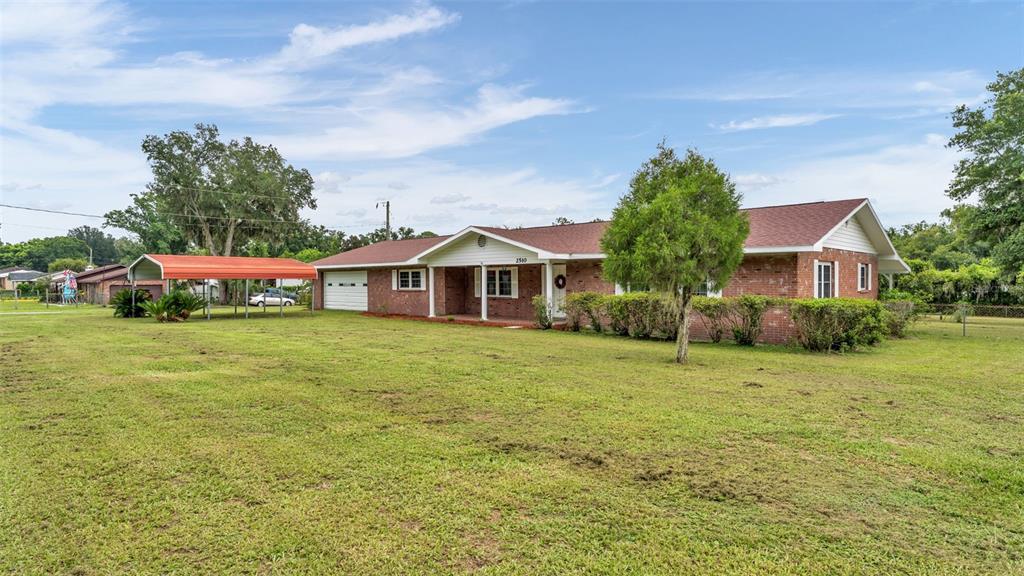 A single-story brick house with a red roof, a front porch, and a metal carport — 2510 GIBSONIA GALLOWAY ROAD, LAKELAND, FL