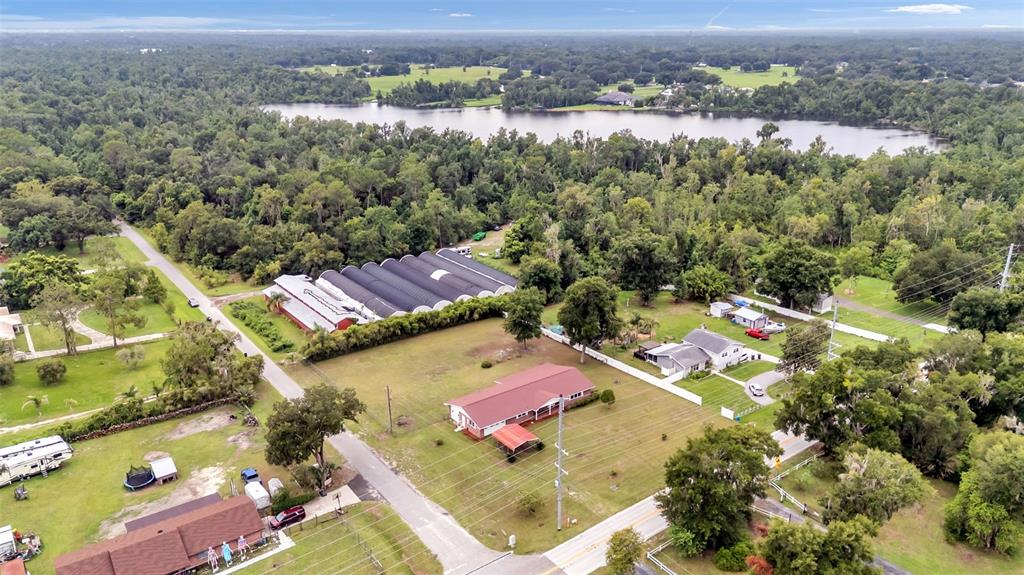 An aerial view shows a residential property with a large greenhouse, houses, and a lake — 2510 GIBSONIA GALLOWAY ROAD, LAKELAND, FL