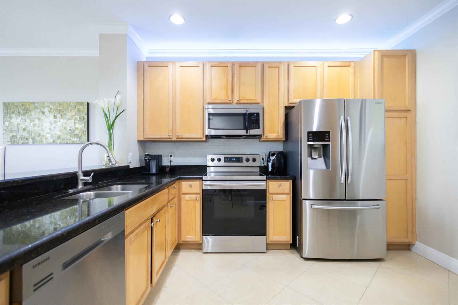 A kitchen features light wood cabinets, stainless steel appliances, and black granite countertops — 8115 Bellagio Lane, Boynton Beach FL 33472, BOYNTON BEACH, FL