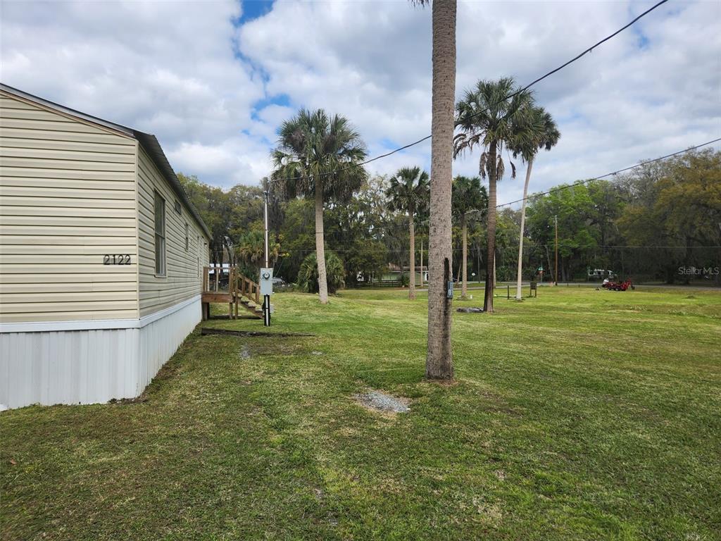 The exterior of a light-colored mobile home sits on a large, grassy lot with palm trees — 2122 CR 426, LAKE PANASOFFKEE, FL