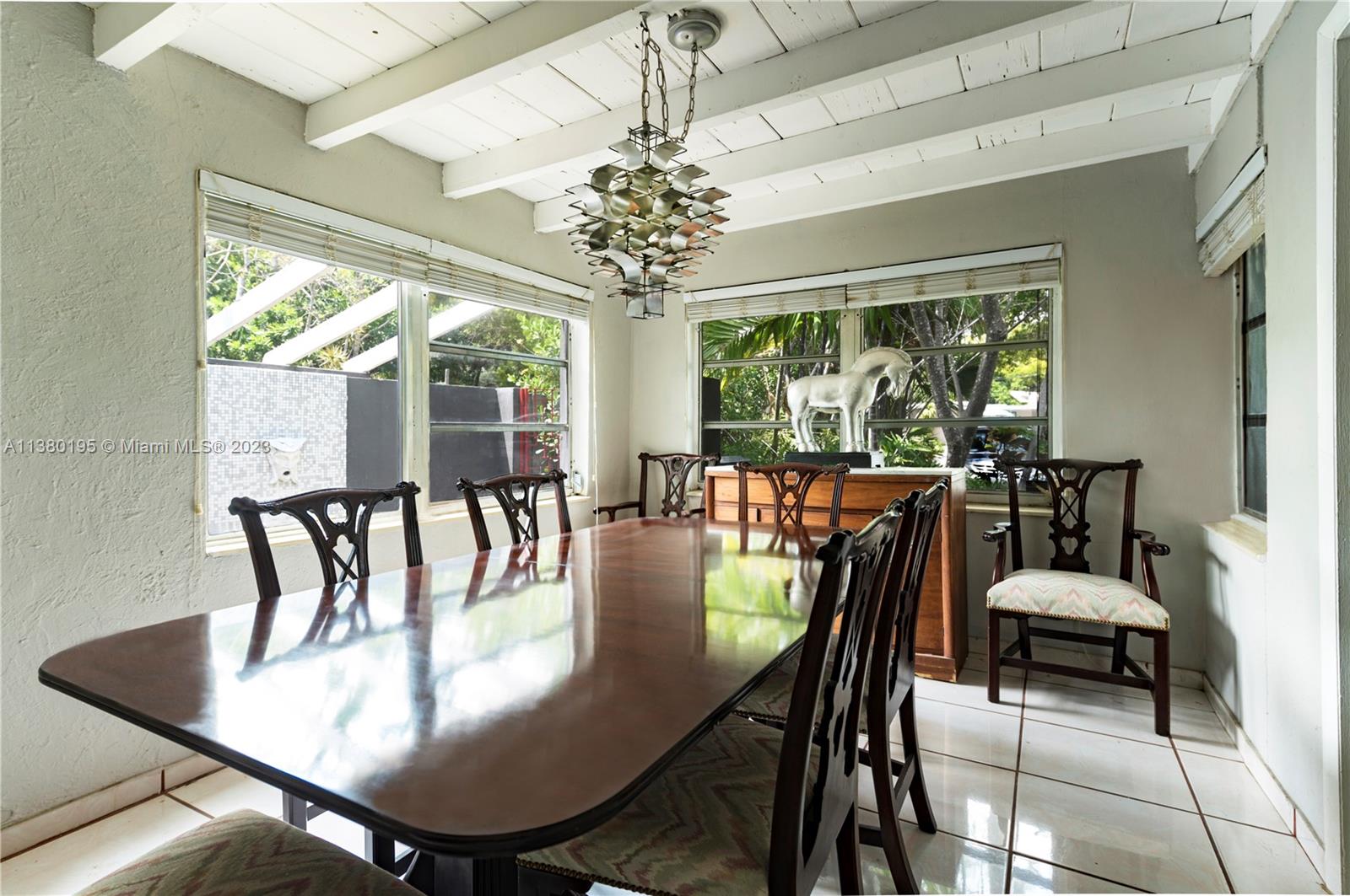 A dining room features a long wooden table, Chippendale-style chairs, and a unique metal chandelier — 2018 Fletcher St, Hollywood FL 33020, HOLLYWOOD, FL