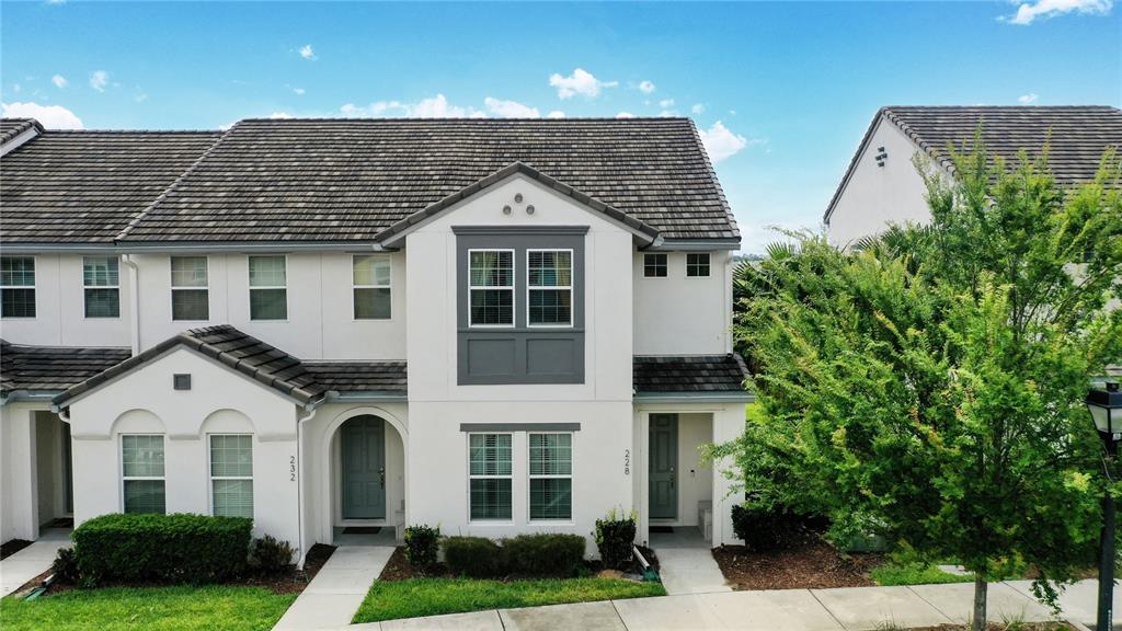 An exterior view of two adjacent two-story townhouses with gray roofs and white stucco walls — 228 CAPTIVA DR, DAVENPORT, FL