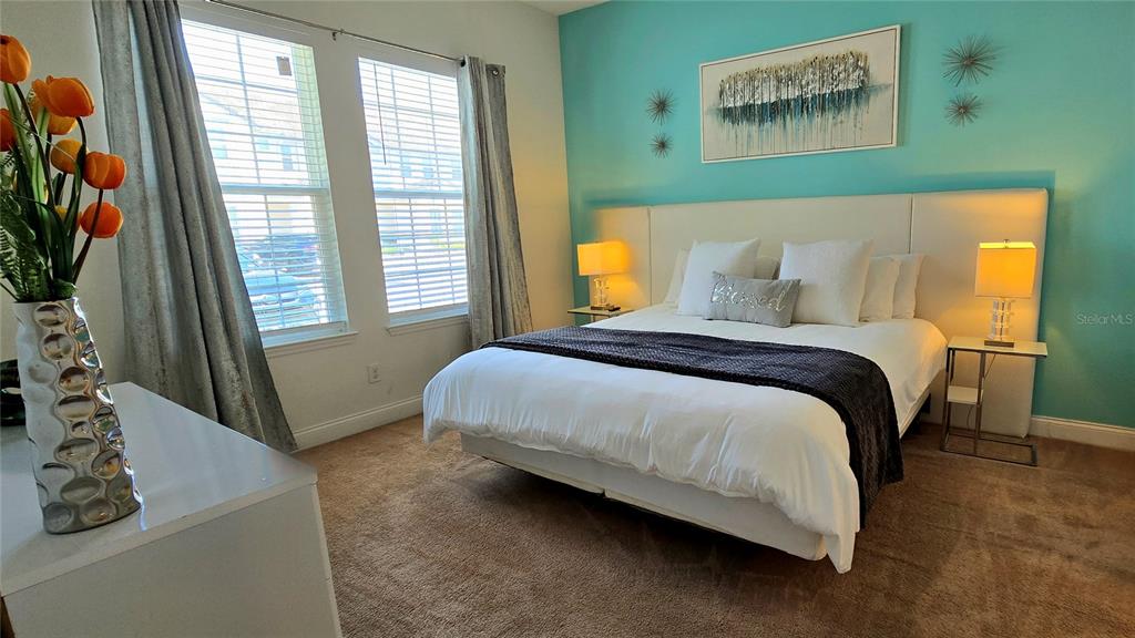 A bedroom features a bed with white bedding, a teal accent wall, and two windows — 228 CAPTIVA DR, DAVENPORT, FL