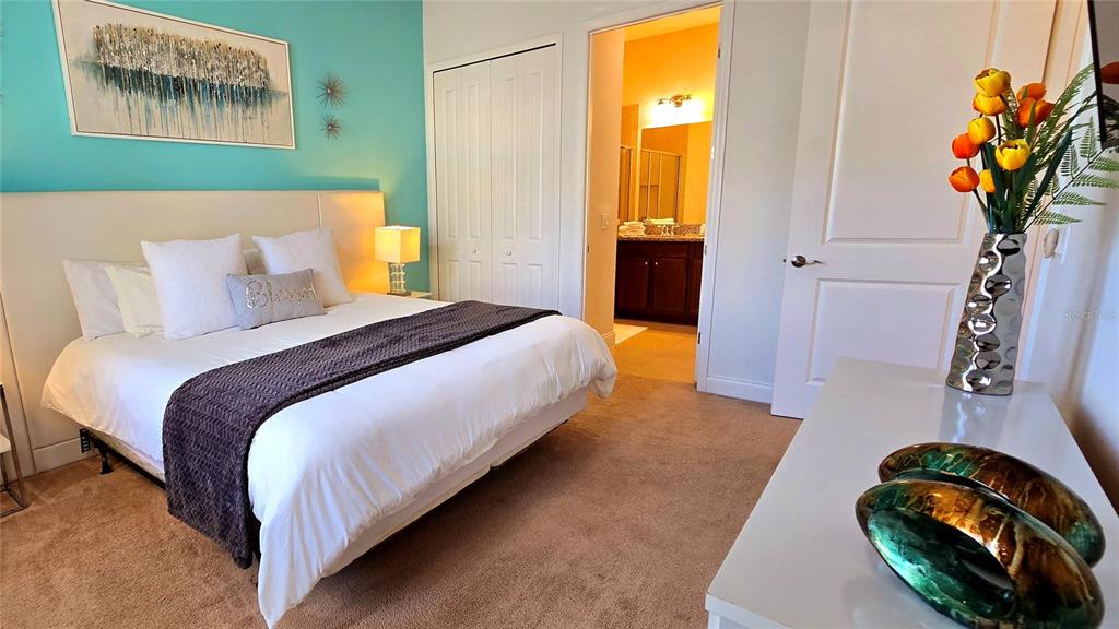 A bedroom features a bed with a dark runner, turquoise accent wall, and an attached bathroom — 228 CAPTIVA DR, DAVENPORT, FL