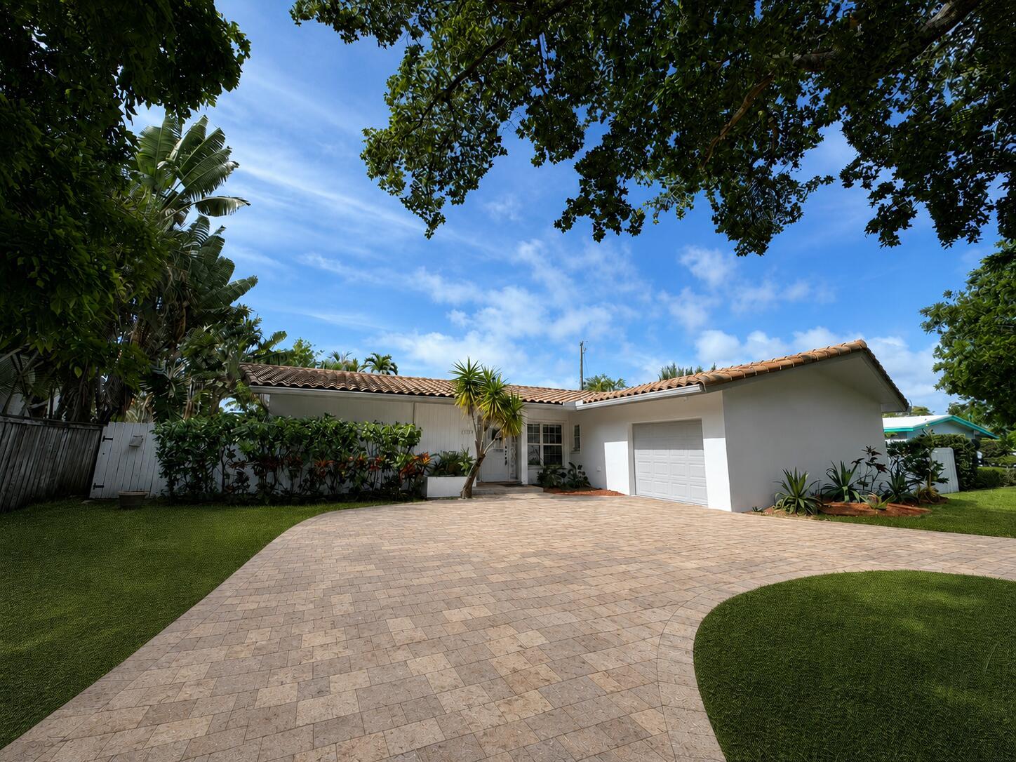 A single-story white house with a tiled roof, paver driveway, and lush tropical landscaping — 3230 Aqua Vista Drive, Pompano Beach FL 33062, POMPANO BEACH, FL