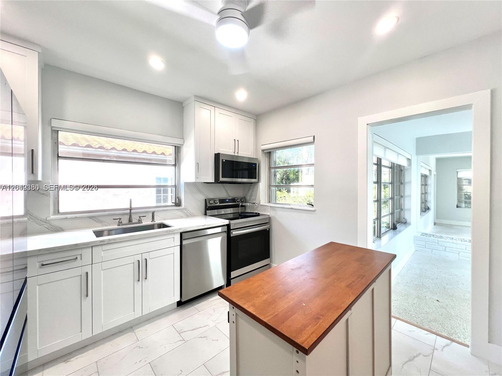 A kitchen features white cabinets, stainless steel appliances, a wooden island, and marble-style flooring — 2245 SW 25th Ter # 0, Miami FL 33133, MIAMI, FL