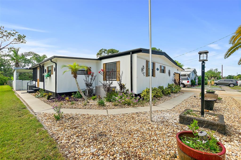 A single-story mobile home features white siding, a gravel yard, and a concrete walkway — 5660 WOOD STREET, PORT ORANGE, FL