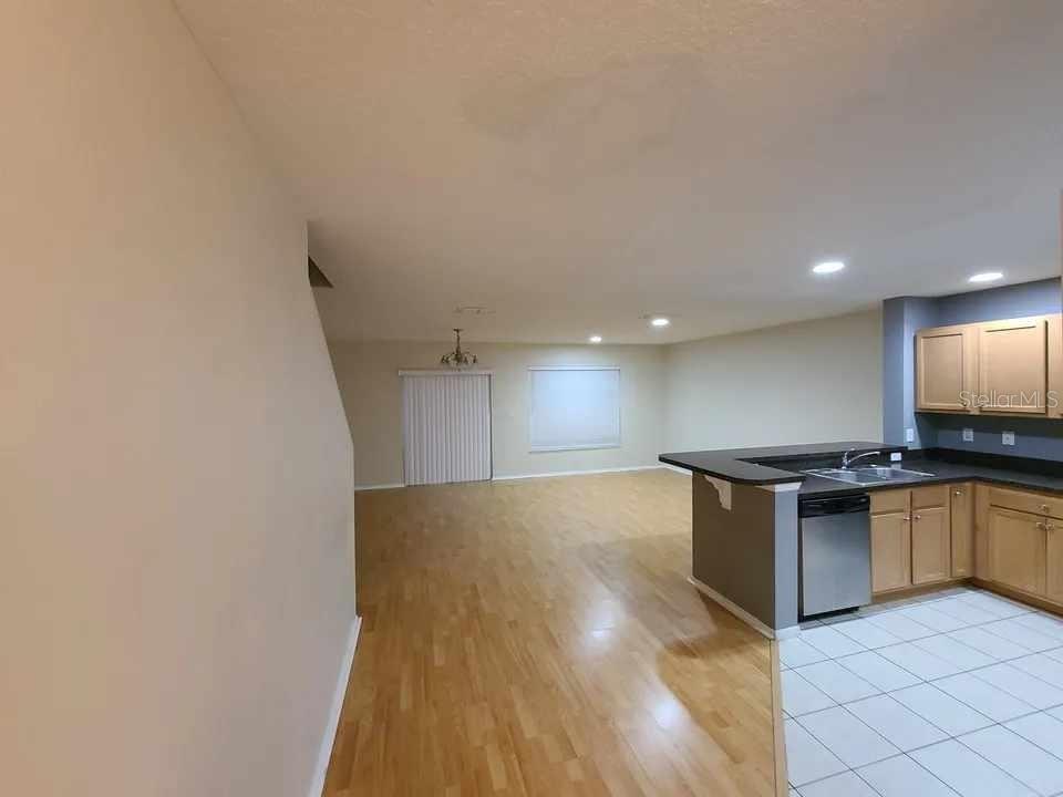 An open-concept living area features hardwood flooring, a kitchen with light wood cabinets, and tile — 1034 CHALCEDONY STREET, KISSIMMEE, FL