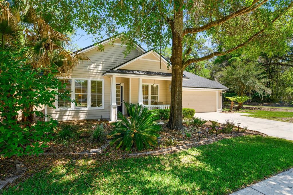 A single-story house with beige siding, a covered front porch, and a two-car garage — 2117 NW 144TH STREET, NEWBERRY, FL