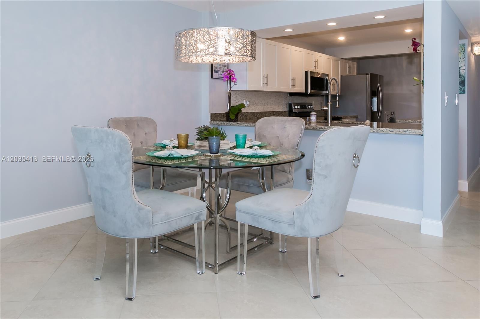 A dining area features a glass-topped table with four upholstered chairs under a decorative chandelier — 14 Royal Palm Way # 601, Boca Raton FL 33432, BOCA RATON, FL