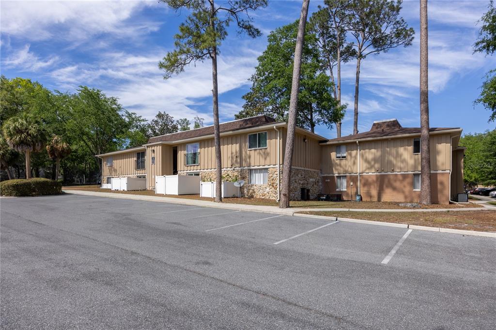 A two-story apartment building with tan vertical siding and a stone facade exterior — 507 NW 39TH ROAD UNIT 114, GAINESVILLE, FL