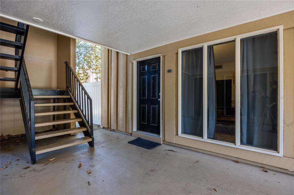An exterior view of a ground-floor apartment entrance with a staircase and large windows — 507 NW 39TH ROAD UNIT 114, GAINESVILLE, FL
