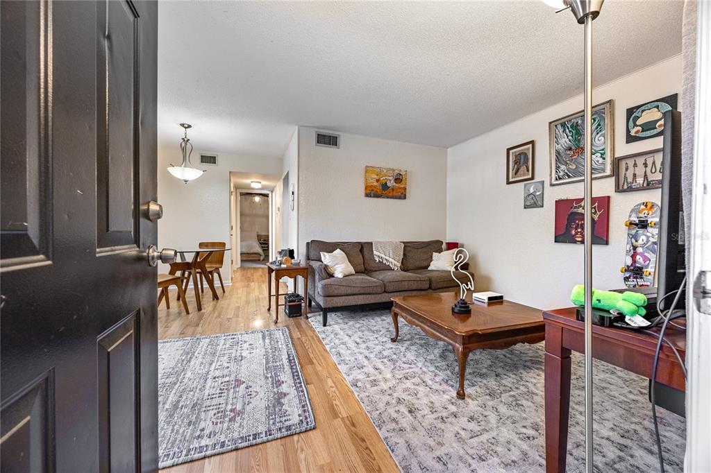 A living room with a brown sofa, wooden coffee table, and hardwood floors — 507 NW 39TH ROAD UNIT 114, GAINESVILLE, FL