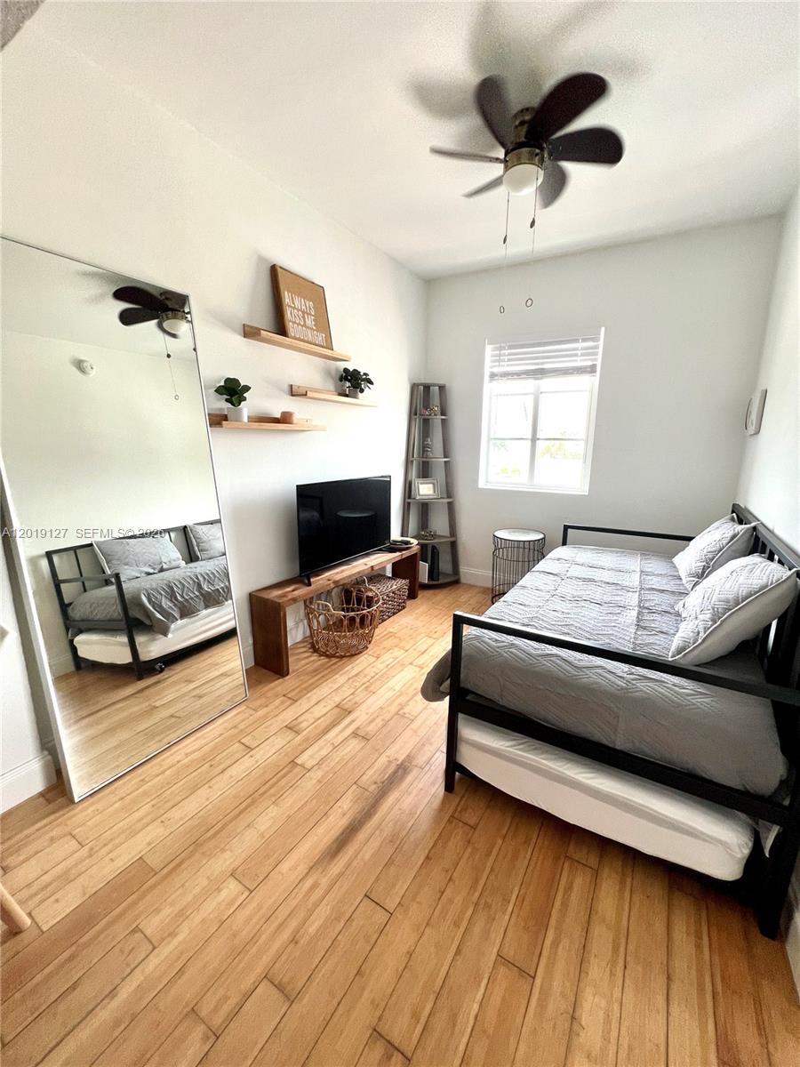 A bedroom features a daybed, a large floor mirror, wood flooring, and a ceiling fan — 8415 Harding Ave # 14, Miami Beach FL 33141, MIAMI BEACH, FL