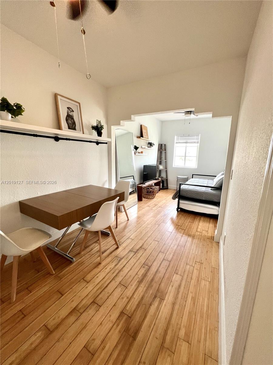 A dining area with a wooden table leads into a bedroom through a stepped archway — 8415 Harding Ave # 14, Miami Beach FL 33141, MIAMI BEACH, FL