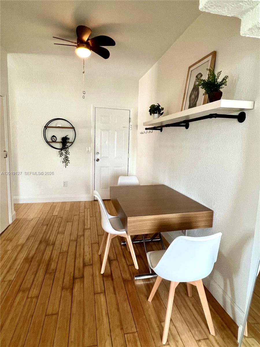 A dining area features a wooden table, white chairs, and a wall-mounted shelf — 8415 Harding Ave # 14, Miami Beach FL 33141, MIAMI BEACH, FL
