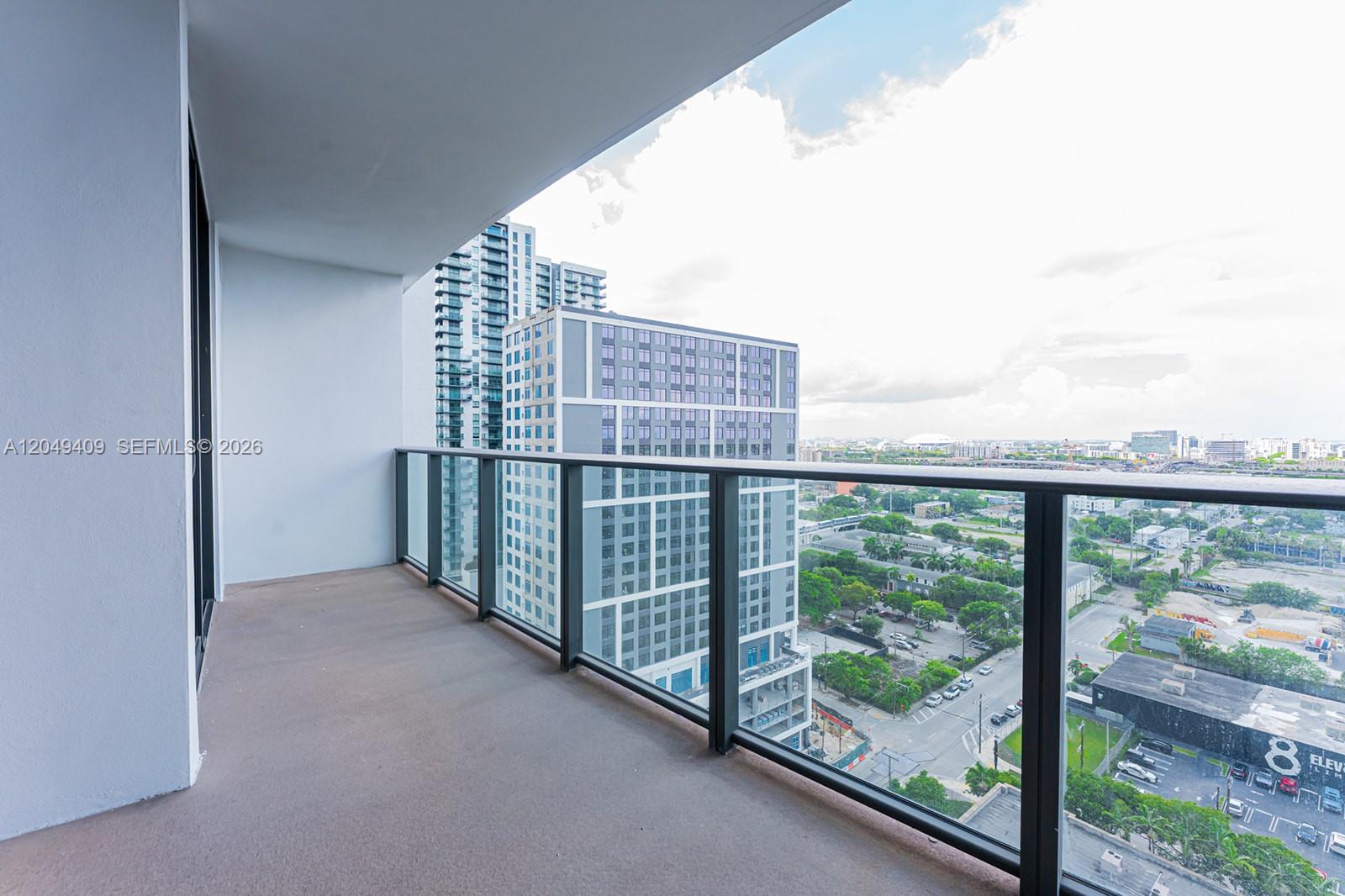 A high-rise balcony features a glass railing overlooking a city street and neighboring buildings — 1600 NE 1st Ave # 1814, Miami FL 33132, MIAMI, FL