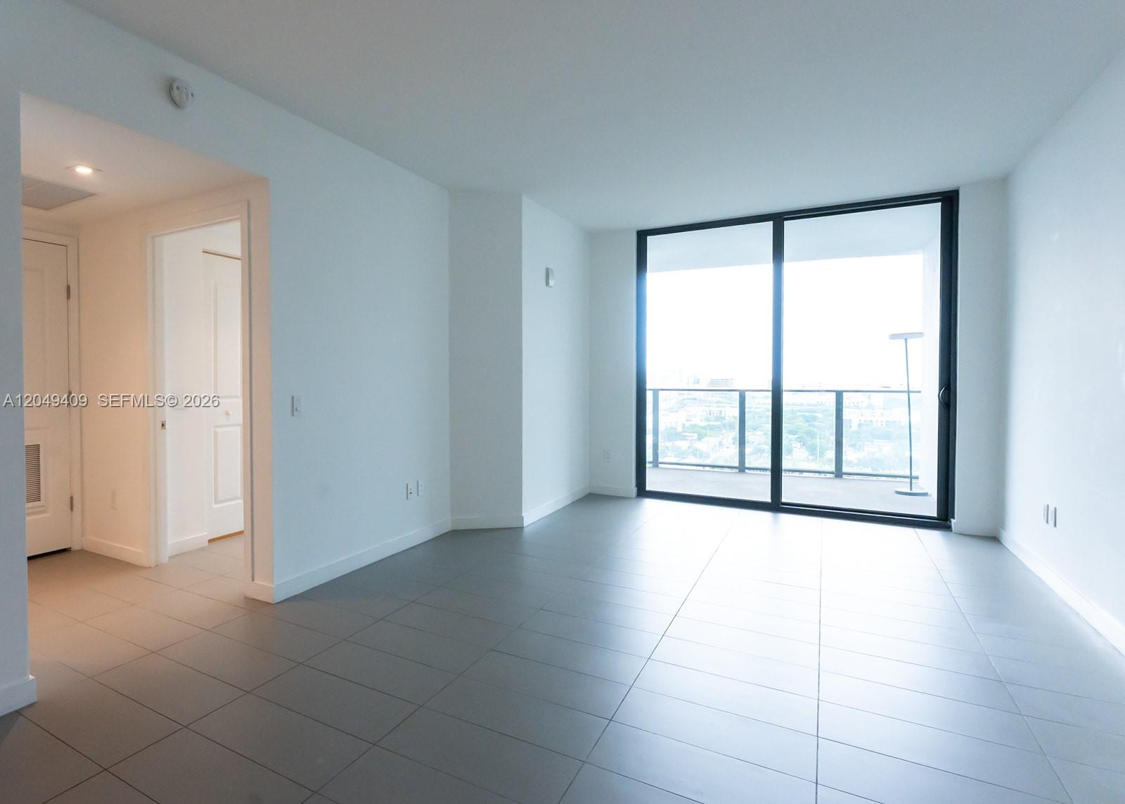 An empty room with gray tile floors, white walls, and a large sliding glass door — 1600 NE 1st Ave # 1814, Miami FL 33132, MIAMI, FL