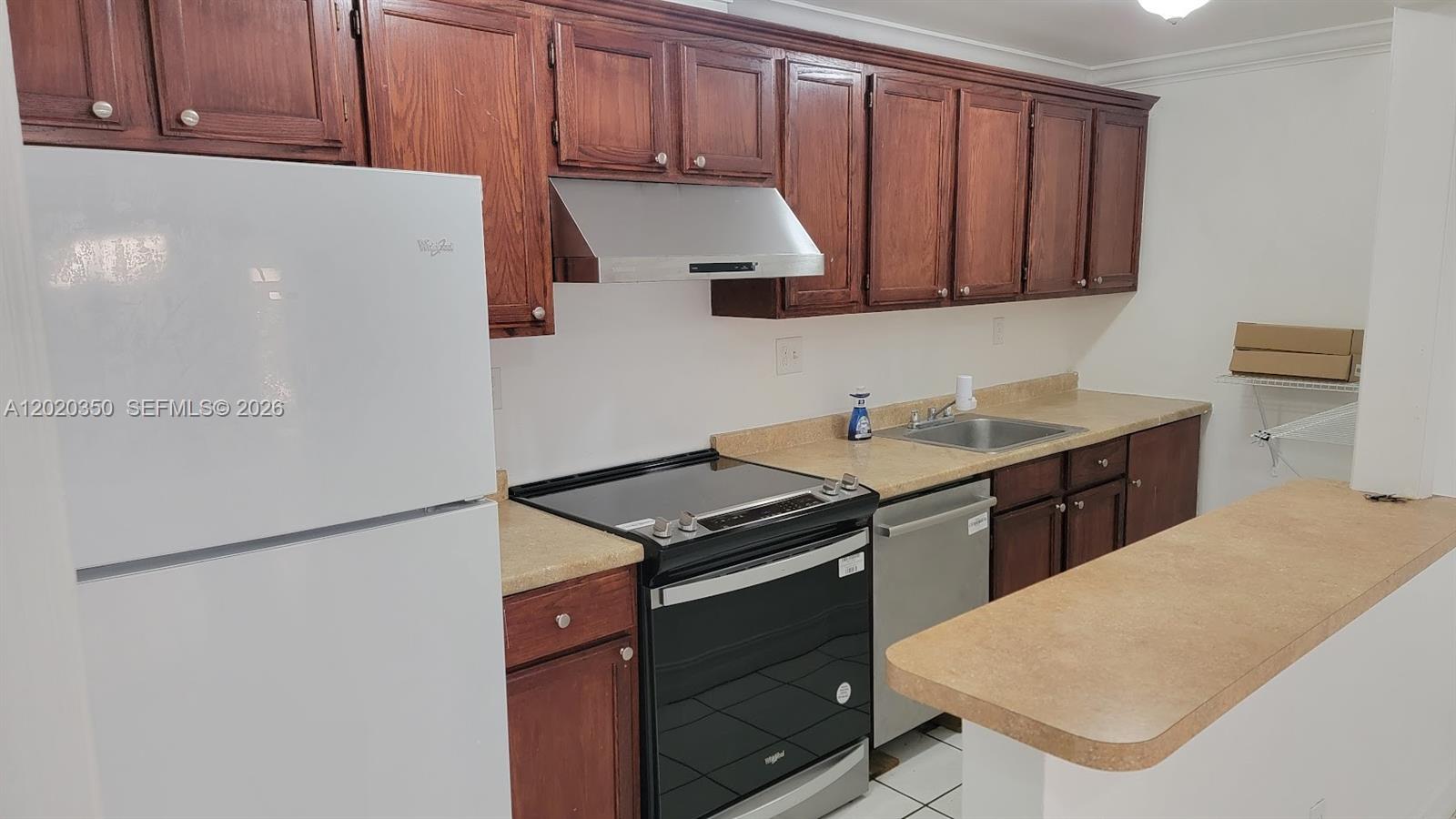 A kitchen features wooden cabinets, a white refrigerator, a black stove, and beige countertops — 4410 NW 79th Ave # 1C, Doral FL 33166, DORAL, FL