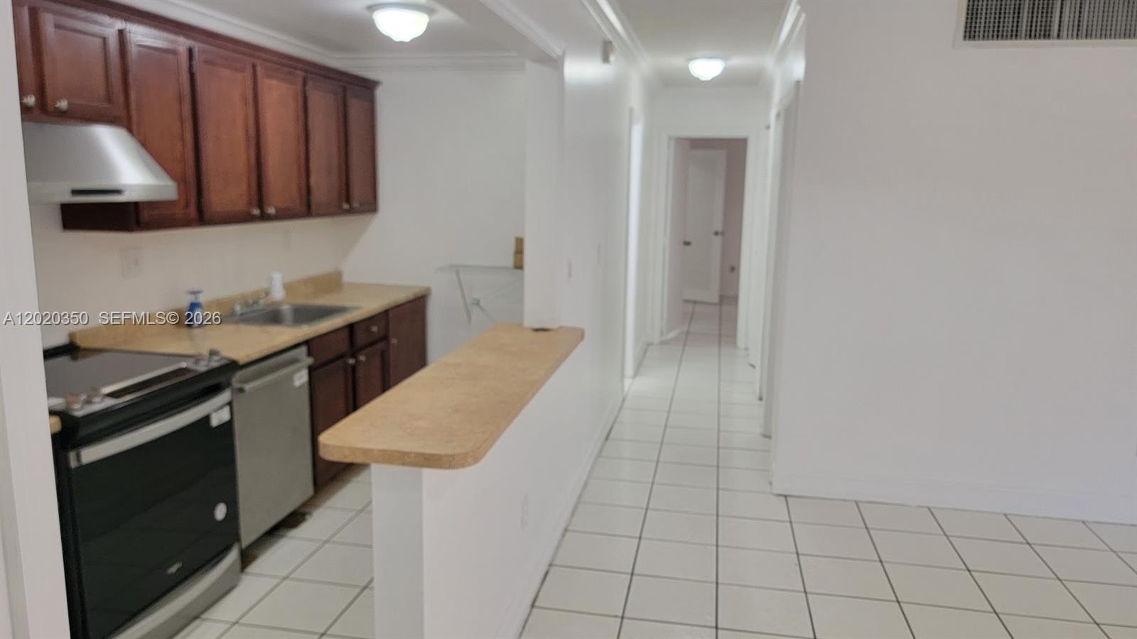 A kitchen features dark wood cabinets, stainless steel appliances, and a breakfast bar — 4410 NW 79th Ave # 1C, Doral FL 33166, DORAL, FL