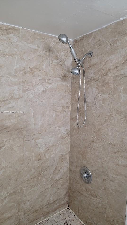 A shower stall features beige marble-look tile walls and a handheld showerhead fixture — 4410 NW 79th Ave # 1C, Doral FL 33166, DORAL, FL
