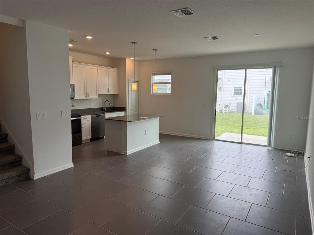 An open-concept kitchen and living area features white cabinetry, a center island, and tile flooring — 7621 DANUBE ROAD, KISSIMMEE, FL