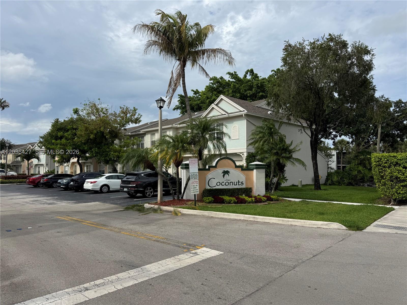A sign for Coconuts stands in front of a residential building with parked cars nearby — 77 SIMONTON CR # 77, Weston FL 33326, WESTON, FL