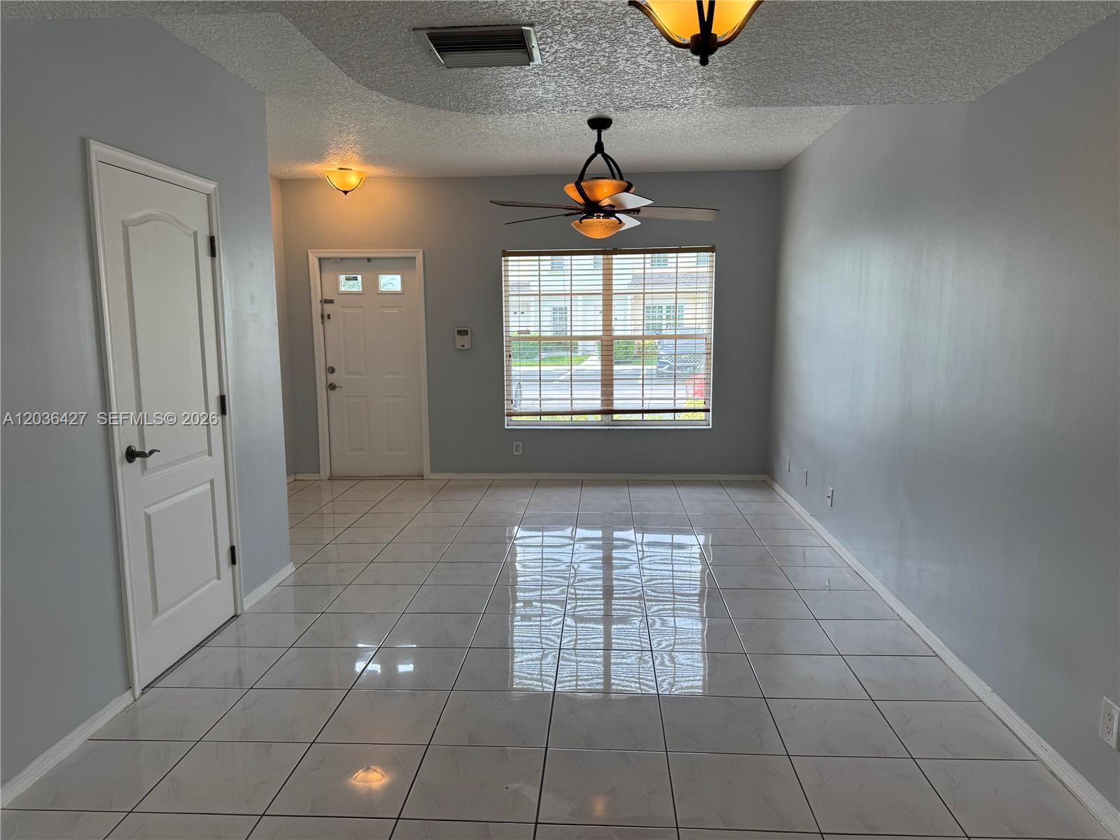 An empty room features light gray walls, white tile flooring, a ceiling fan, and a window — 77 SIMONTON CR # 77, Weston FL 33326, WESTON, FL