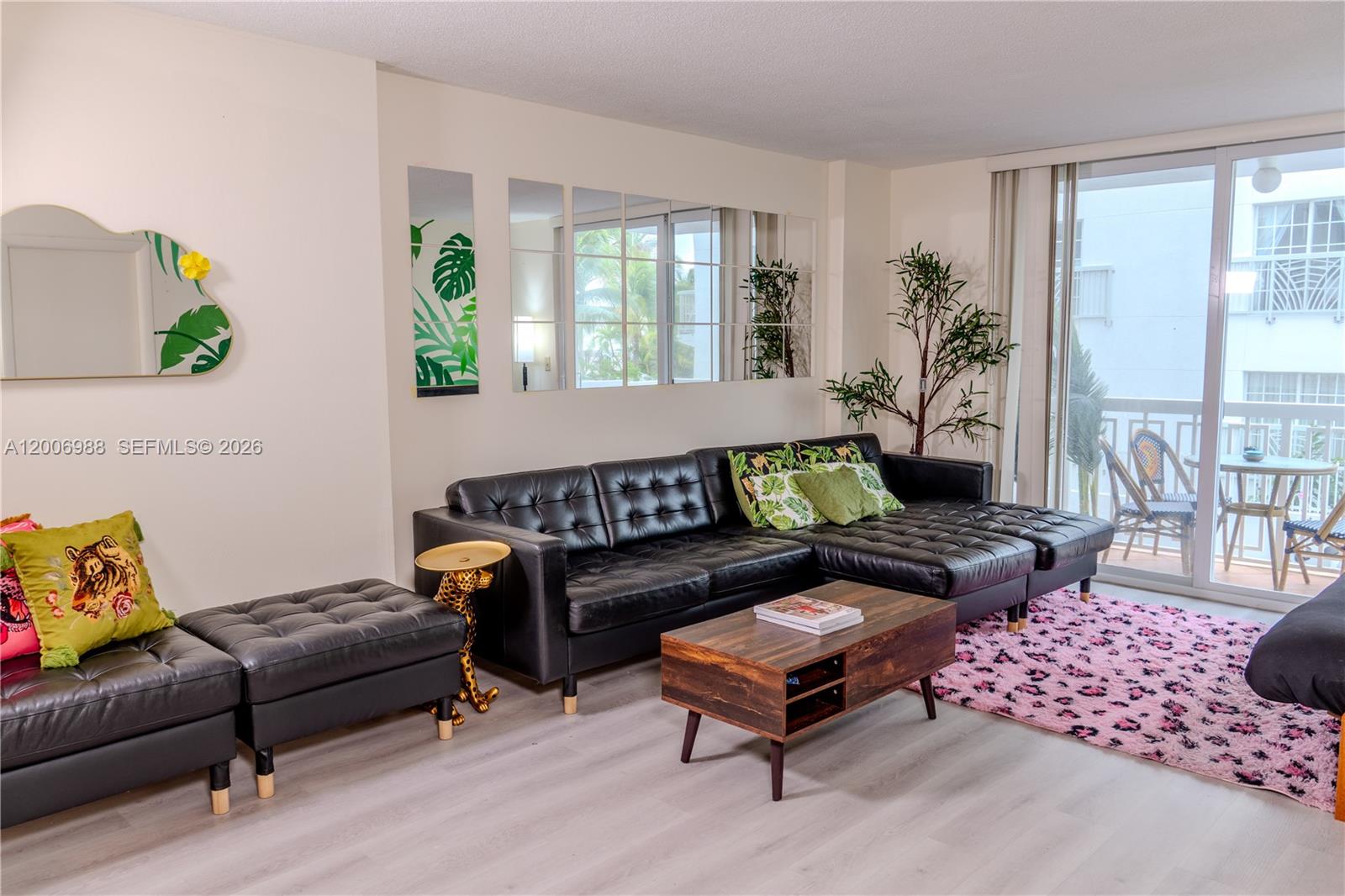 A living room features a black leather sectional, a wooden coffee table, and a pink rug — 401 Ocean Dr # 222, Miami Beach FL 33139, MIAMI BEACH, FL