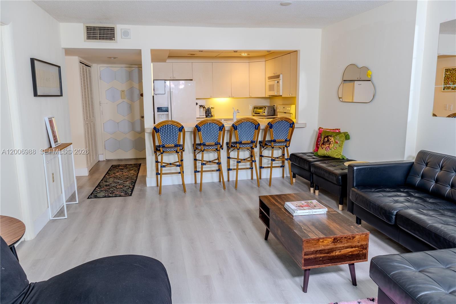 A living room features light wood flooring, a kitchen breakfast bar, and black leather furniture — 401 Ocean Dr # 222, Miami Beach FL 33139, MIAMI BEACH, FL