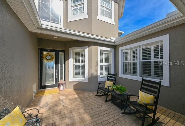 A paved courtyard features a front door, two rocking chairs, and windows with white shutters — 10119 DEERCLIFF DR, TAMPA, FL