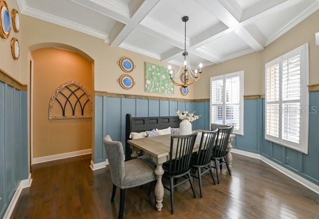 A dining room features blue wainscoting, a coffered ceiling, a chandelier, and a wooden table — 10119 DEERCLIFF DR, TAMPA, FL