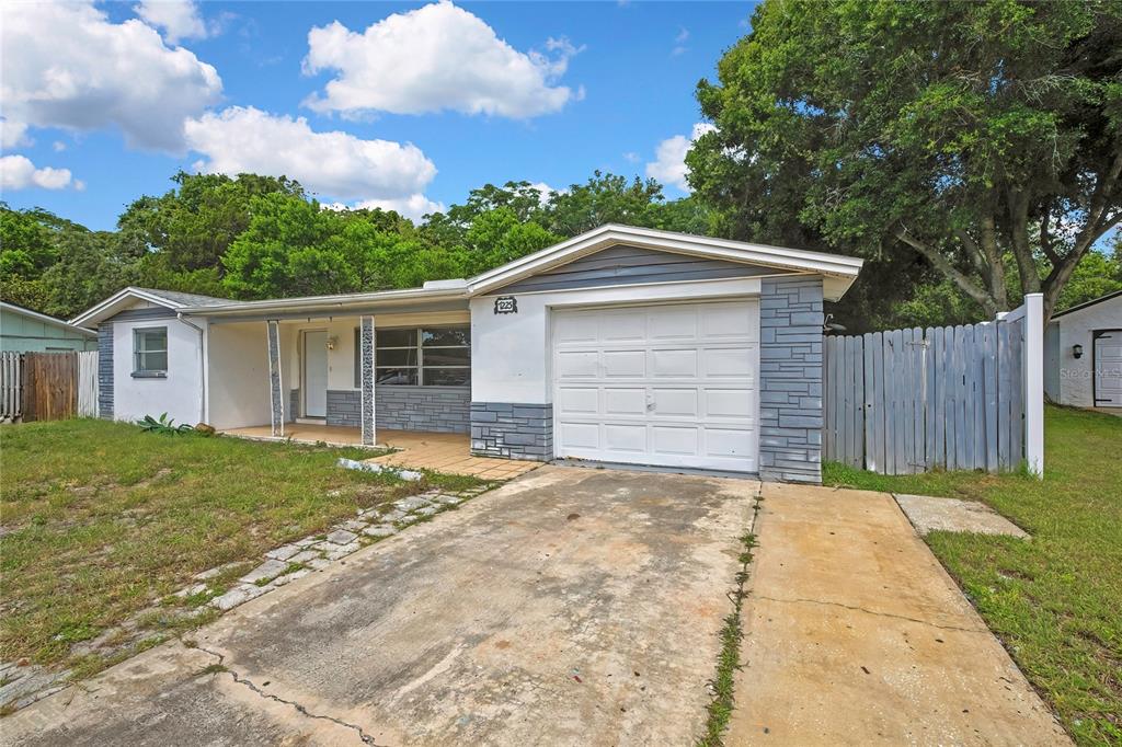 A single-story house with a white garage door, stone accents, and a concrete driveway — 7225 SEASHORE DRIVE, PORT RICHEY, FL
