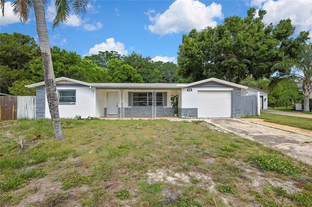 A single-story house with a white exterior, gray stone accents, and a concrete driveway — 7225 SEASHORE DRIVE, PORT RICHEY, FL