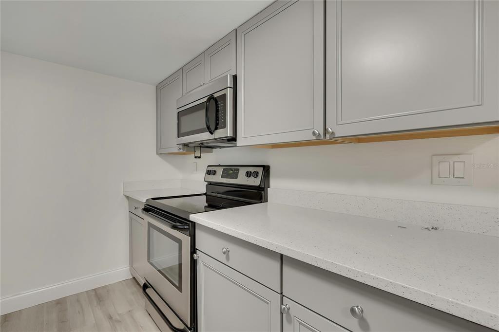 A kitchen features gray cabinets, stainless steel appliances, and white countertops — 7225 SEASHORE DRIVE, PORT RICHEY, FL