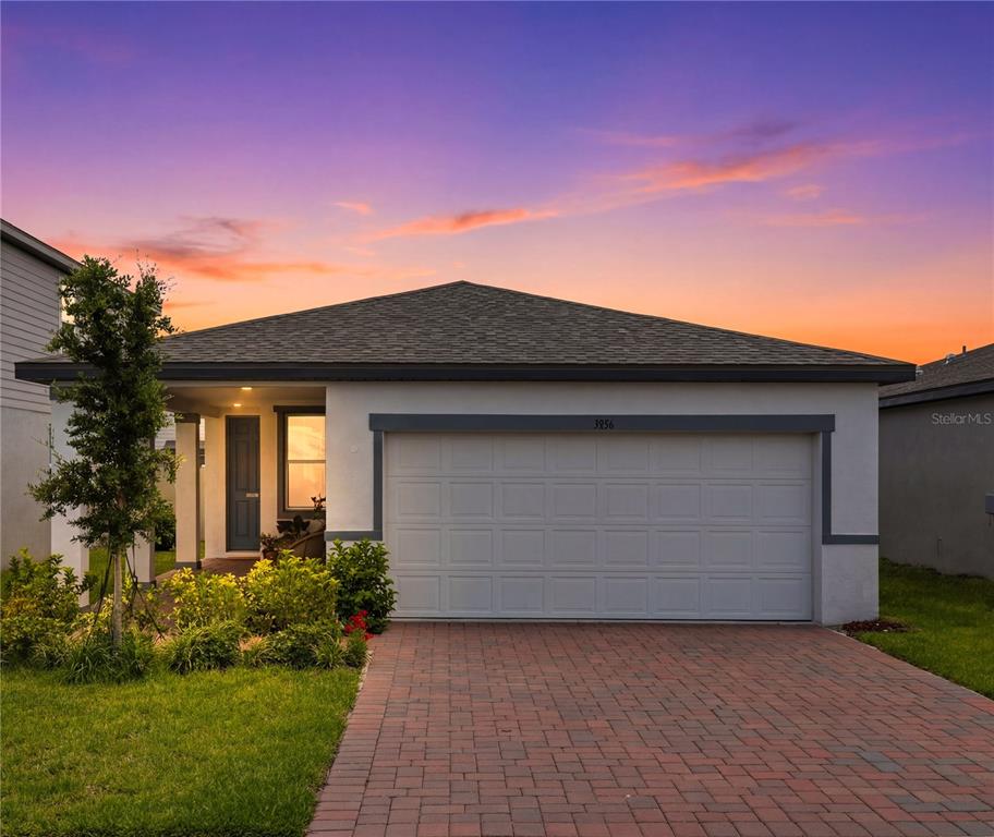 A single-story house with a two-car garage and a brick paver driveway at sunset — 3856 GIORGIO DRIVE, WINTER HAVEN, FL