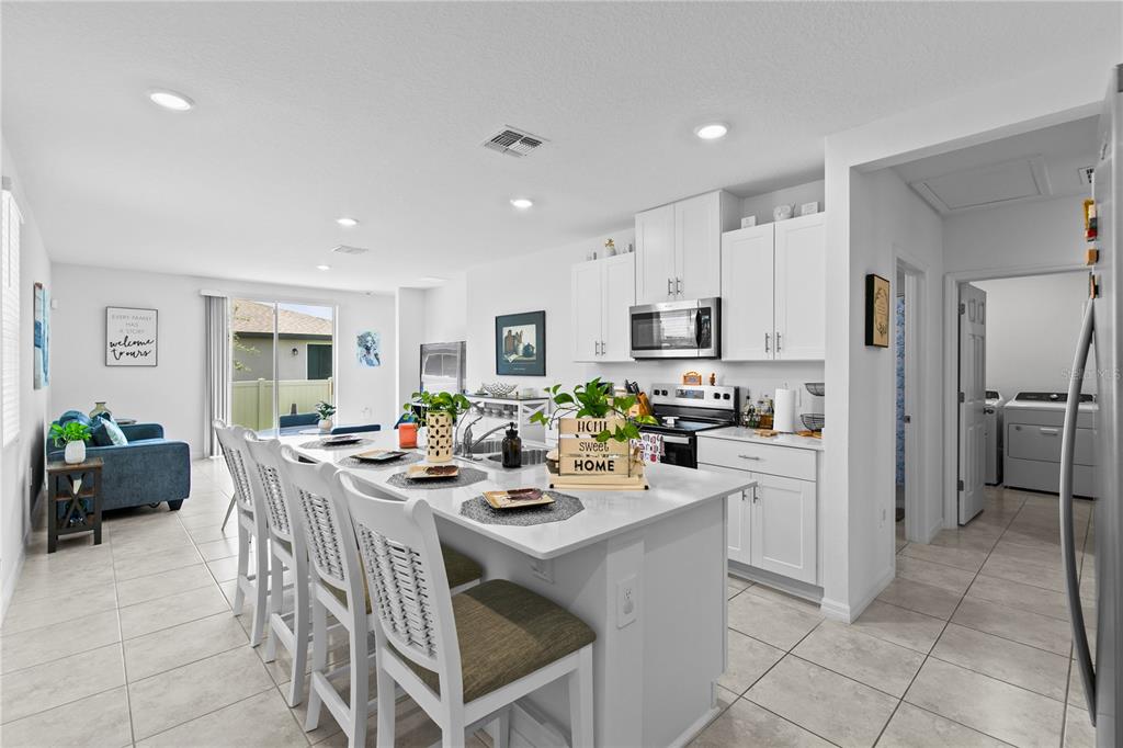 A kitchen with a white island and stools opens into a living area with tile floors — 3856 GIORGIO DRIVE, WINTER HAVEN, FL