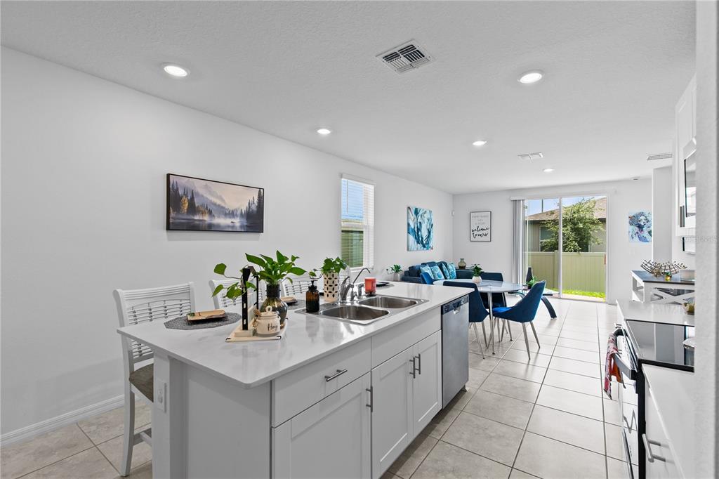 A kitchen island with a white countertop sits in an open-concept room with tile flooring — 3856 GIORGIO DRIVE, WINTER HAVEN, FL