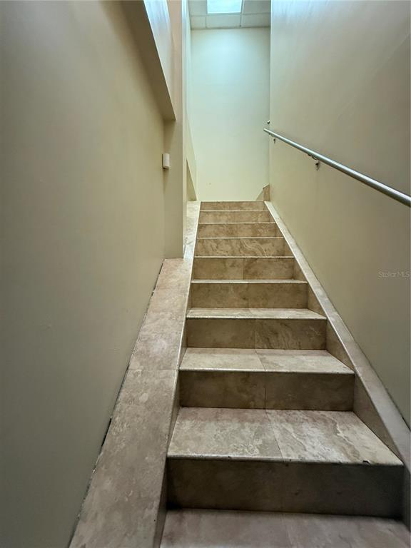 A staircase with tan stone steps and a metal handrail leads upward between two walls — 177 CALLE ROMERILLO, SAN JUAN, PR