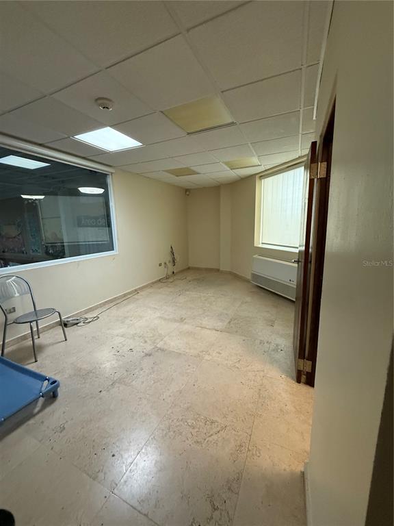 An empty office room features a drop ceiling, tile flooring, and a large window — 177 CALLE ROMERILLO, SAN JUAN, PR