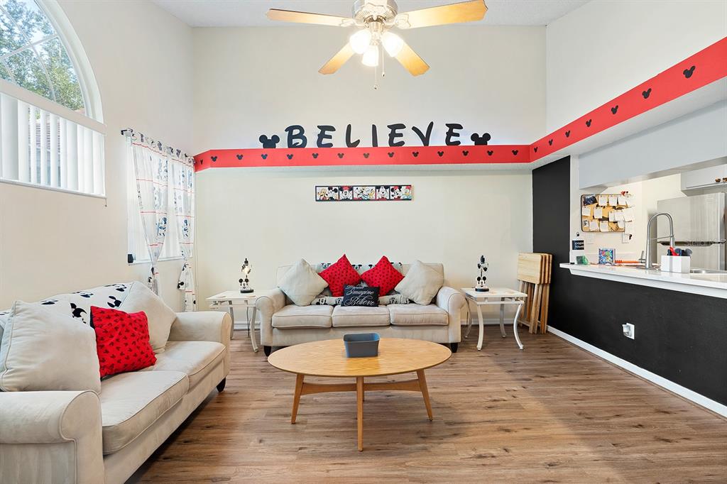 A living room features a Disney-themed red border, a ceiling fan, and two beige sofas — 2735 N POINCIANA BOULEVARD UNIT 100, KISSIMMEE, FL